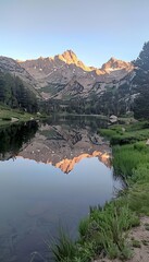 Obraz premium Serene lake enclosed by majestic mountains with shimmering reflections on calm water surface