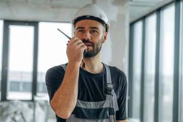 Talking by using walkie talkie. A man is renovating an unfinished room