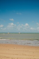 Serene beach scene with boats and blue sky.