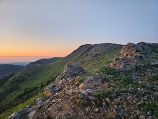 Naklejka premium Early morning sunrise nature landscape taken at the top of a large hill covered in green grass.