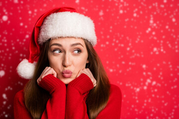 Photo of flirty young lady hands face blow kiss wear holiday sweater cap isolated on red color background