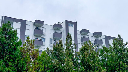 Photo of Modern Apartment Building with Greenery . Contemporary Architecture Surrounded by Lush Trees. Rainy cloudy day.