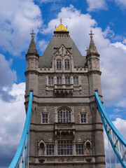Fototapeta premium A striking stock photo featuring the first tower of the iconic Tower Bridge in London, UK. The image showcases the impressive architectural detail of the tower, set against a backdrop of a cloudy sky.