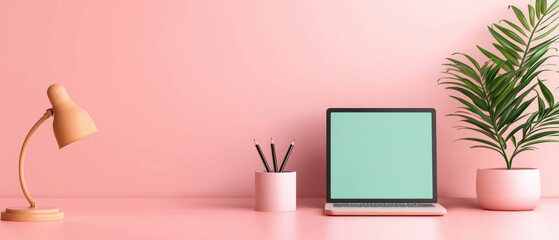 A stylish workspace featuring a laptop, desk lamp, pencil holder, and a green plant, all set against a soft pink background.
