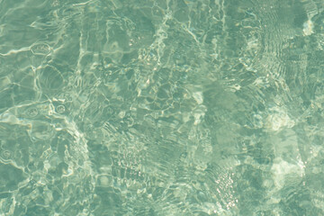 Blue water with ripples on the surface. Defocus blurred transparent blue colored clear calm water surface texture with splashes and bubbles. Water waves with shining pattern texture background.