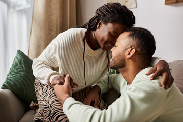 Happy couple enjoys each others company in their cozy living room, embracing warmth and love.