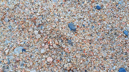 Stones and sand in the summer day. Yellow sand on the beach near a sea.