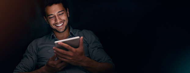 Night, happy and man with tablet, creative and smile for content creation, mockup and browsing. Space, entrepreneur and joy for audience engagement, banner and person with social media in dark office