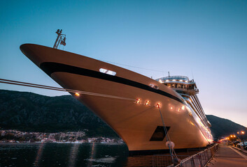 An elegant cruise liner docked at twilight, its lights shimmering against the evening sky,...