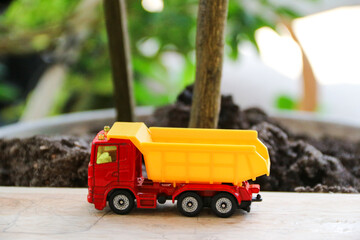 Children's toy colored small truck on the grass background of sand and stones loaded with cargo