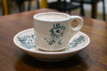 A glass of antique ceramic coffee cup on a teak wood table