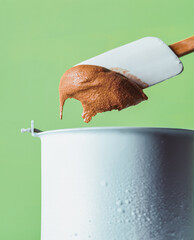Homemade Creamy Chocolate Ice Cream. A frozen container contains a thick, creamy homemade chocolate ice cream that is stirred with a wooden spoon