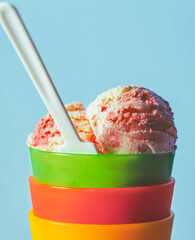 Colorful Ice Cream Scoops In Stacked Cups With A Spoon. Three scoops of strawberry ice cream in stacked bowls are topped with a small spoon.