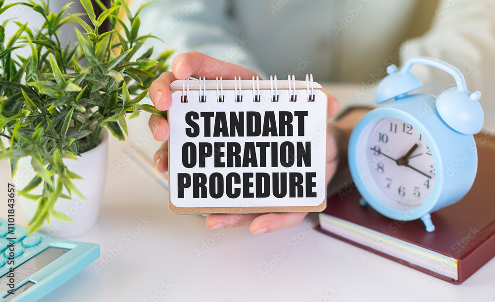 Poster notepad with text standart operation procedure in hands with calculator, alarm clock and pen. white 