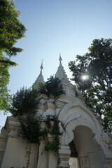 A towering white temple with intricate carvings and golden spires, framed by lush green trees and a clear blue sky, creating a sense of awe and tranquility.