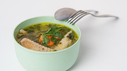Homemade chicken soup in a bowl on a white background