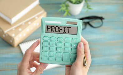 PROFIT text written on a calculator next to the background of euro banknotes.