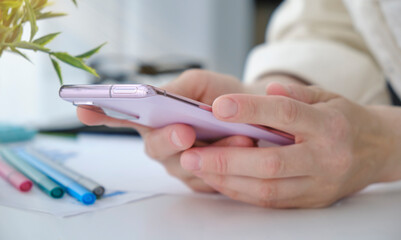 Close-up, business woman using smartphone, touching on screen, surfing the internet at modern office, searching data or social networks concept