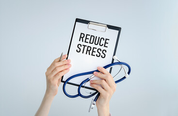 Clipboard with text REDUCE STRESS with doctor woman and stethoscope.