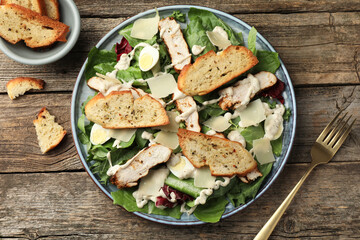 Tasty Caesar salad with chicken served on wooden table, flat lay