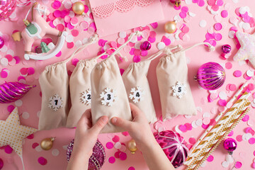Christmas advent calendar with gift velvet bags on a pink background. Environmentally friendly.