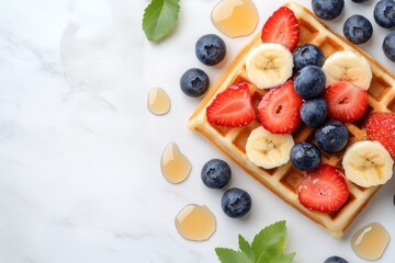 Delicious breakfast with waffles topped with fresh fruit and syrup on a light background