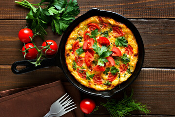 Frittata with tomatoes and spinach in frying pan