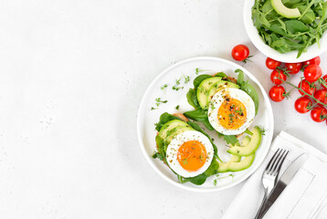 Fried eggs, avocado and greens on bread