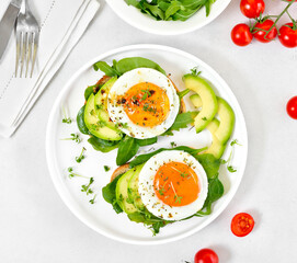 Fried eggs, avocado and greens on bread