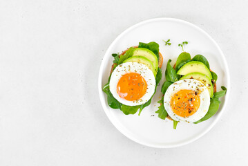 Fried eggs, avocado and greens on bread