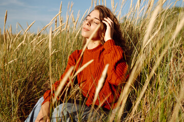 Happy woman enjoying nature outdoors in tall grass. Flying hairs. Outdoor. Fashion style.