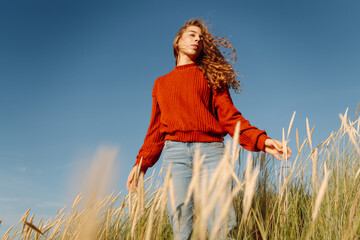 Happy woman enjoying nature outdoors in tall grass. Flying hairs. Outdoor. Fashion style.