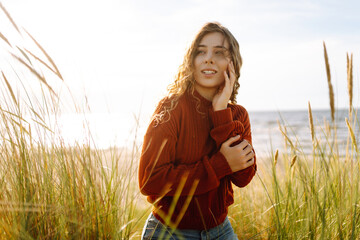 Happy woman enjoying nature outdoors in tall grass. Flying hairs. Outdoor. Fashion style.