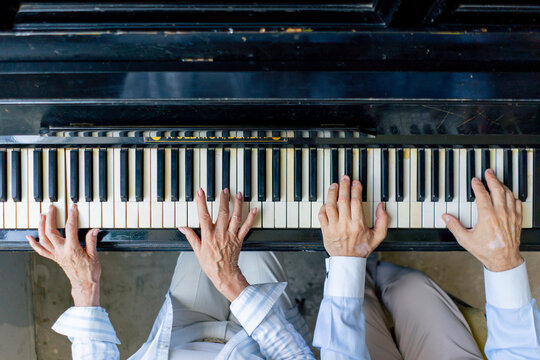 top shot hands close up elderly people sitting at the piano together playing a melody learning new chords old age memories of an elderly couple pleasant leisure time in old age warm feelings support