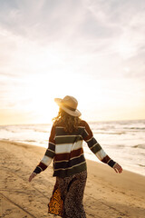 Beautiful curly woman on the beach in cold sunny weather. Spring time. Lifestyle, travel, tourism, nature, active life.