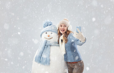 Happy young Social media influencer travel woman taking a selfie with a snowman in a winter...