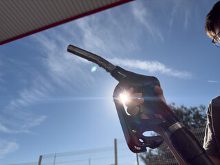 A person is holding a gas pump with the sun shining on it