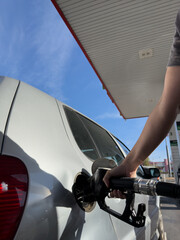 A person is filling up a car with gas at a gas station