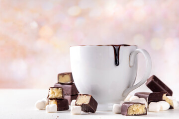 Marzipan hot chocolate, on table with ingredients, marshmallows and marzipan chocolates. Winter and Christmas comfort tasty hot cocoa drink in white cup