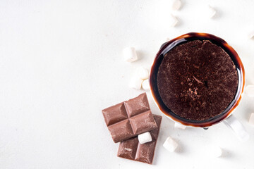 Marzipan hot chocolate, on table with ingredients, marshmallows and marzipan chocolates. Winter and Christmas comfort tasty hot cocoa drink in white cup