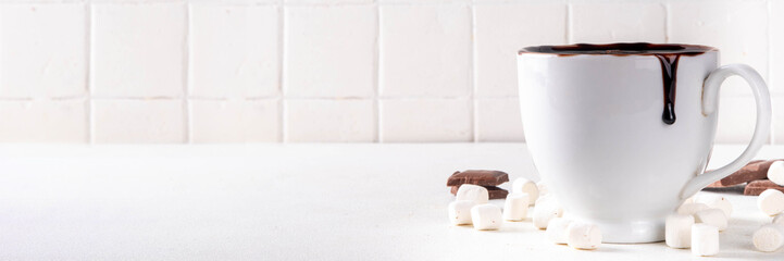 Marzipan hot chocolate, on table with ingredients, marshmallows and marzipan chocolates. Winter and Christmas comfort tasty hot cocoa drink in white cup