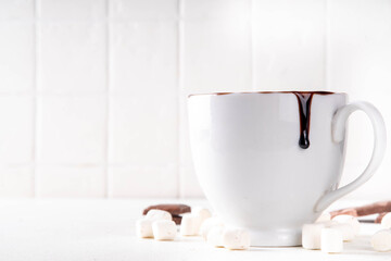 Marzipan hot chocolate, on table with ingredients, marshmallows and marzipan chocolates. Winter and Christmas comfort tasty hot cocoa drink in white cup