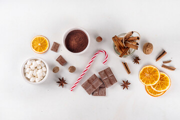 Ingredients for making hot chocolate, traditional winter cocoa tasty drink. Chocolate pieces, cocoa powder, milk, marshmallows, spices, cinnamon, nuts, dried orange, top view copy space