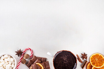 Ingredients for making hot chocolate, traditional winter cocoa tasty drink. Chocolate pieces, cocoa powder, milk, marshmallows, spices, cinnamon, nuts, dried orange, top view copy space