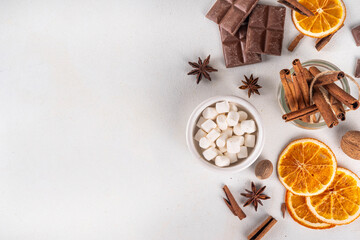 Ingredients for making hot chocolate, traditional winter cocoa tasty drink. Chocolate pieces, cocoa powder, milk, marshmallows, spices, cinnamon, nuts, dried orange, top view copy space