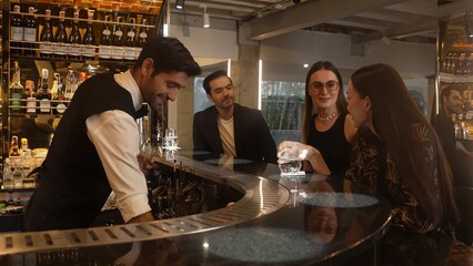 Smart bartender with VIP customer at luxurious bar greeting new beautiful guest at counter in engaging lively conversation at back view in lighting atmosphere at lighting warm nightclub. Vinosity.