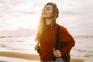 Portrait of woman enjoying a breezy day near a vibrant red lighthouse at sunset. Travel, weekend,...
