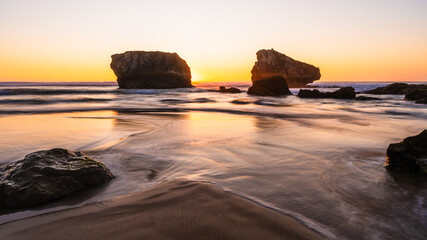 Wide angle view over rocks on a beach at sunset, Biarritz, France.