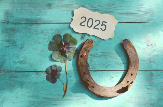 Horseshoe with lucky clover - 2025 greeting card horseshoe on wooden background - happy new year greetings, wishes
