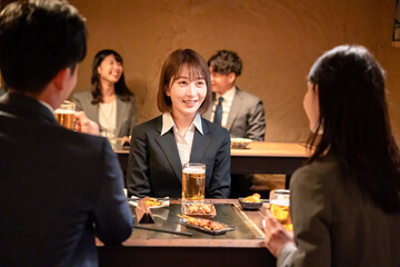 居酒屋で先輩社員とお酒を飲む新入社員